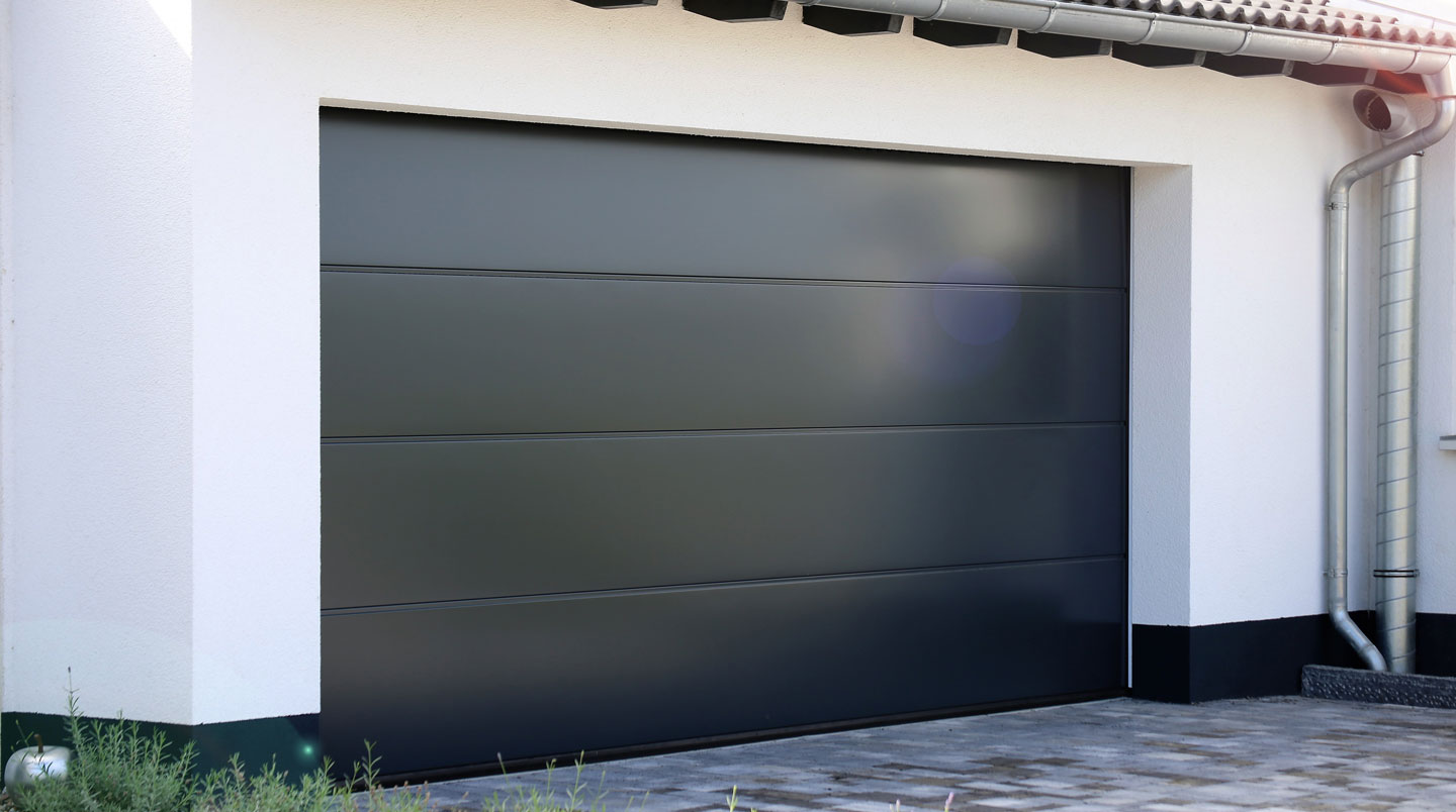 Coupe transversale panneau porte sectionnelle isolé révélant structure sandwich acier-polyuréthane-acier, règle visible pour échelle